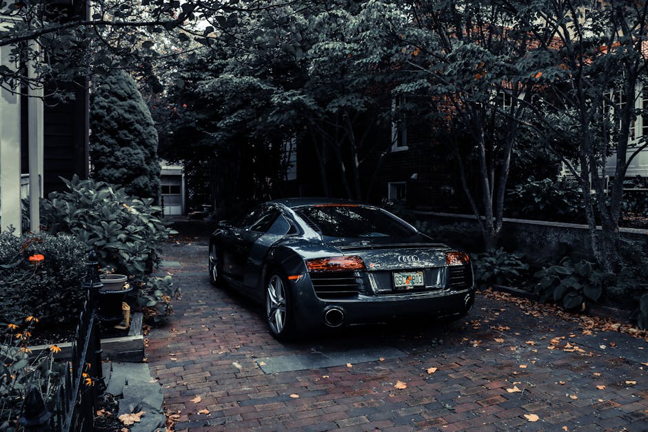 A sleek Audi R8 parked in a leafy residential driveway in Cape May, NJ, showcasing elegance and luxury.