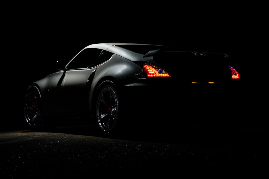 A dramatic shot of a Nissan 370Z sports car illuminated in darkness with vibrant tail lights