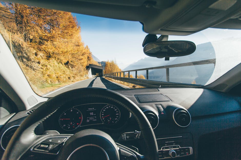 View from car interior driving through a scenic mountain road with autumn foliage and clear skies